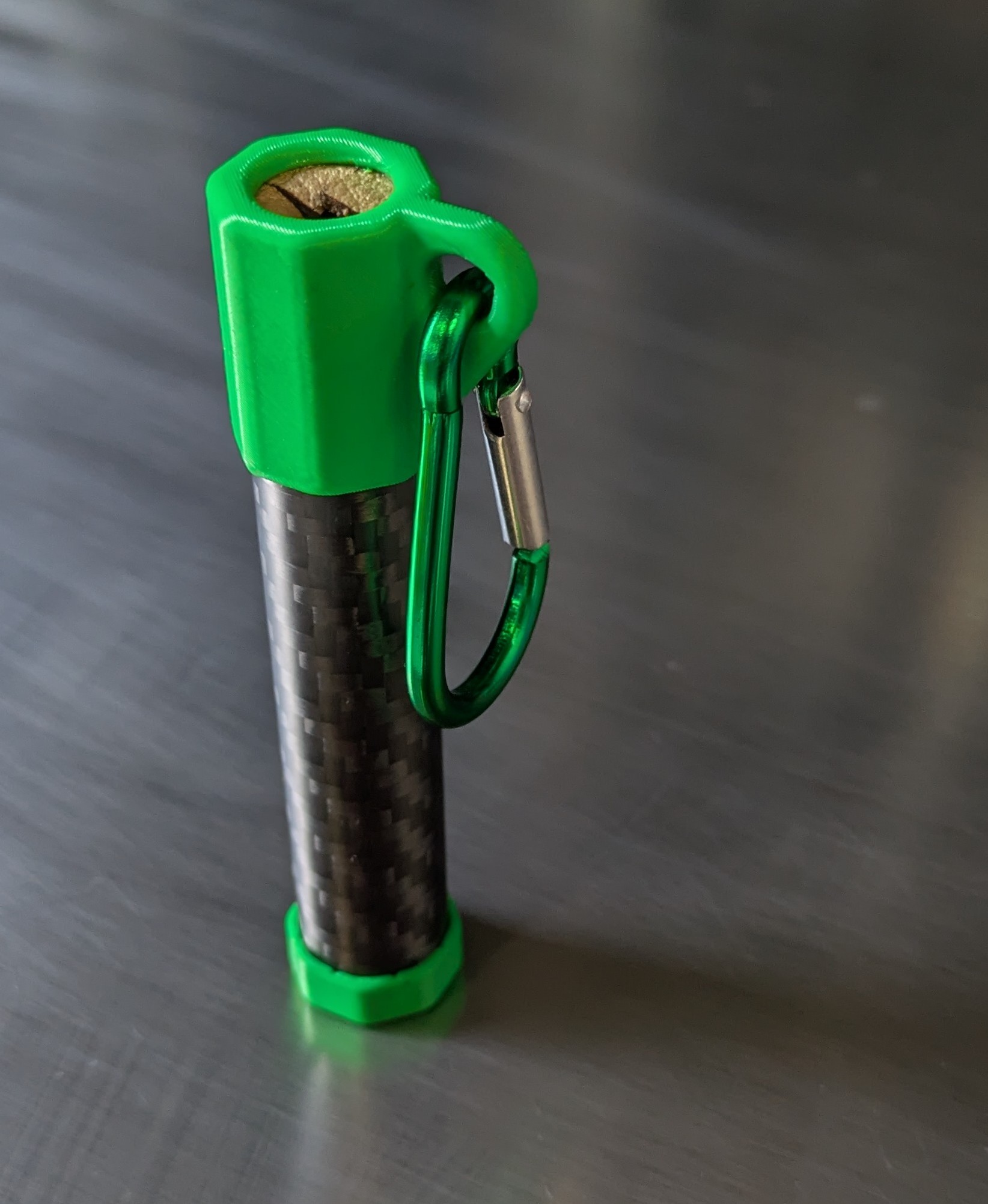 Green NockWorks SlyAro arrow lubricator pod with carbon-fibre tube and carabiner, shown upright